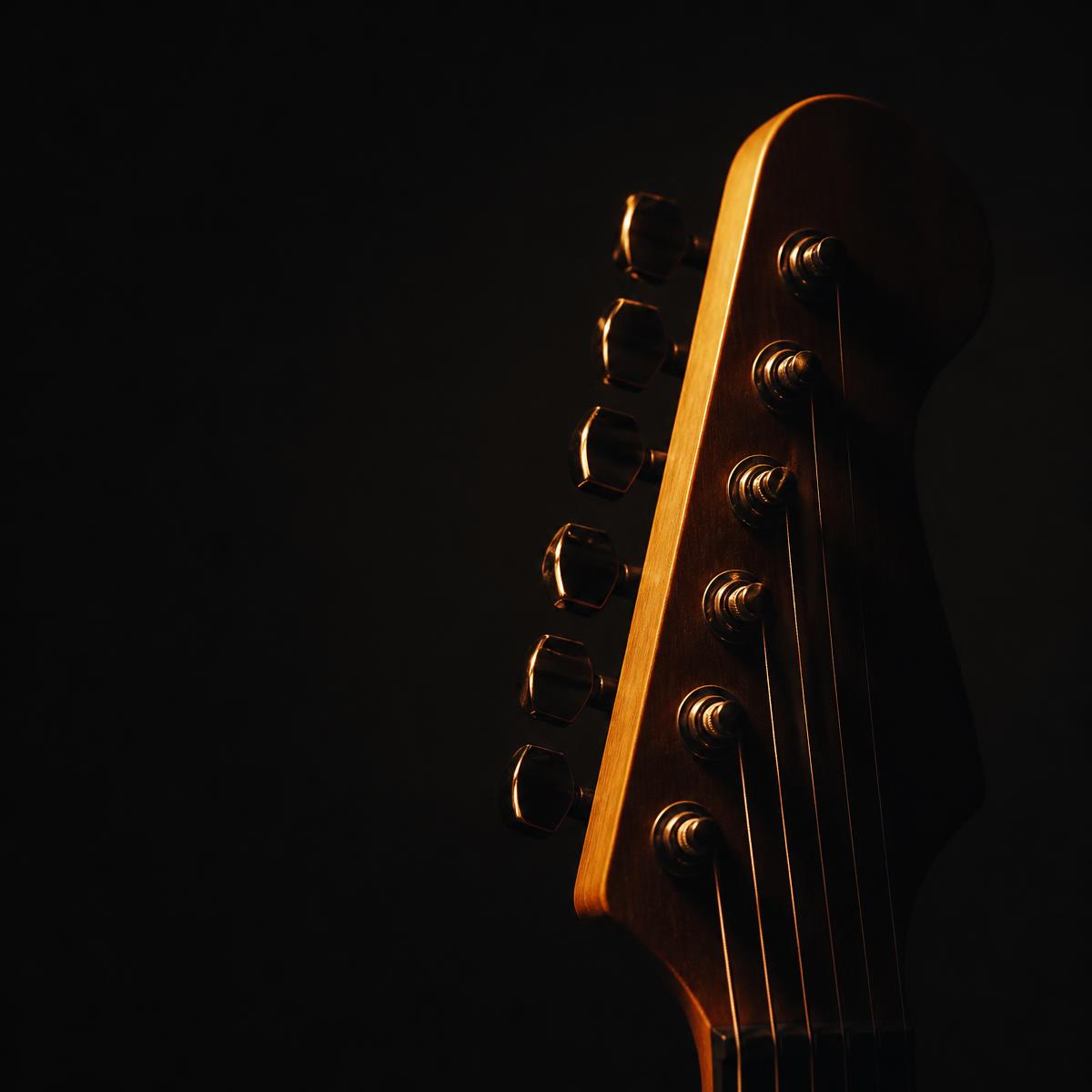 Close-up of an electric guitar headstock lit with warm light